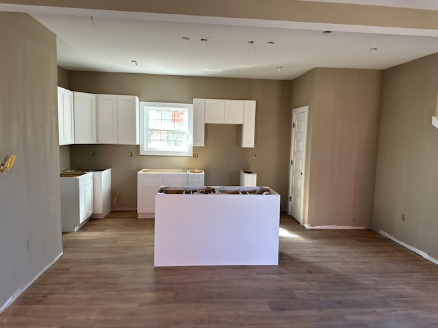 kitchen featuring white cabinets, a center island, baseboards, and wood finished floors