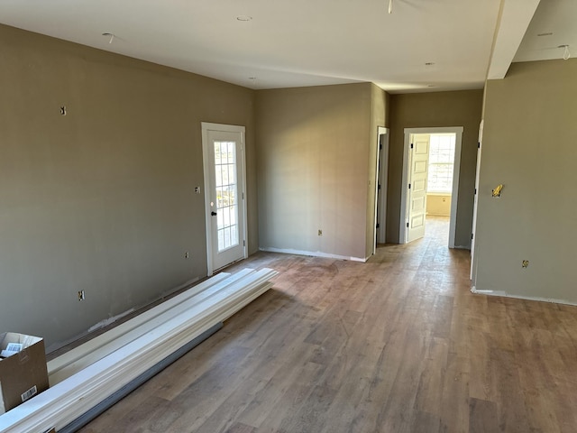 spare room with baseboards and wood finished floors