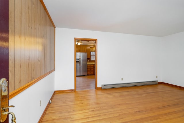 empty room with light hardwood / wood-style flooring and baseboard heating