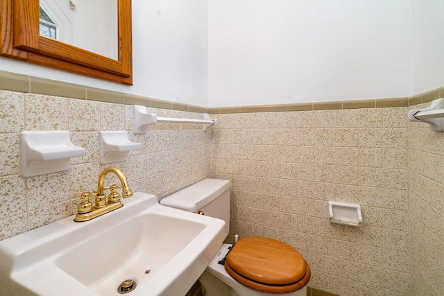 bathroom with sink, tile walls, and toilet