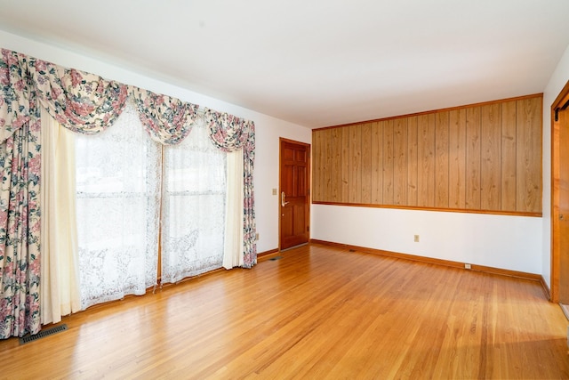 empty room featuring wooden walls and light hardwood / wood-style flooring