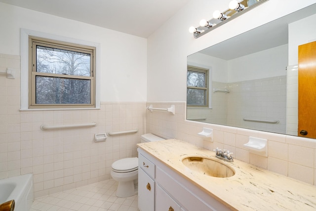 bathroom featuring tile patterned flooring, a tub to relax in, toilet, vanity, and tile walls