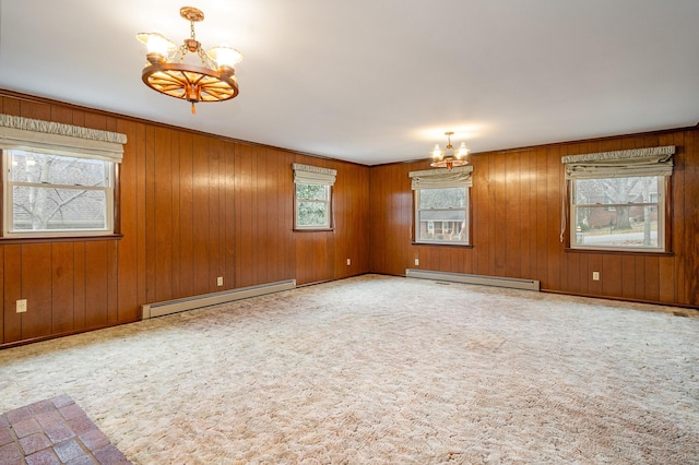 carpeted spare room featuring wooden walls, a chandelier, and a baseboard radiator