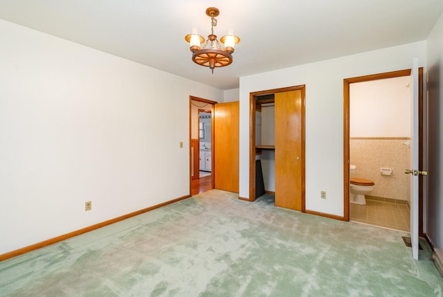 unfurnished bedroom with carpet, ensuite bath, and a notable chandelier