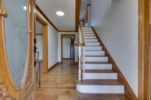 stairway with crown molding and wood-type flooring