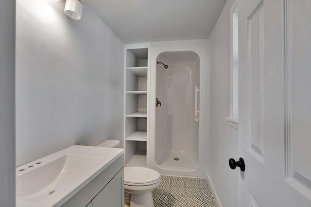 bathroom with tile patterned flooring, vanity, toilet, and walk in shower