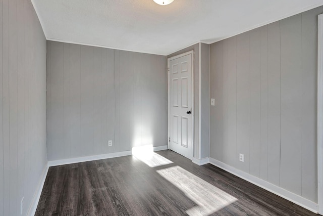 unfurnished room with dark wood-type flooring and wood walls