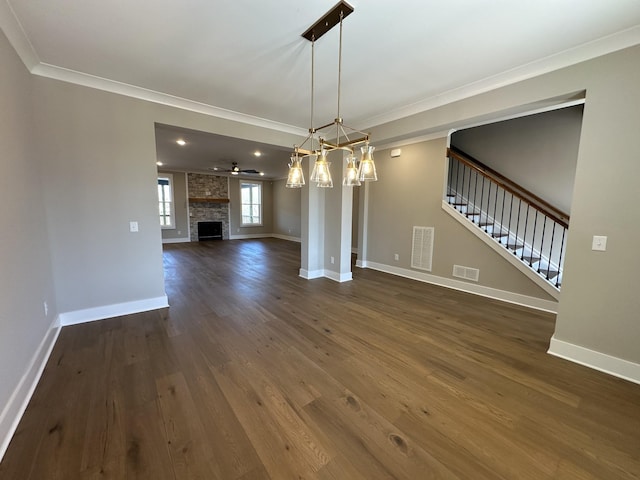 unfurnished dining area with dark hardwood / wood-style flooring, a large fireplace, ceiling fan, and crown molding