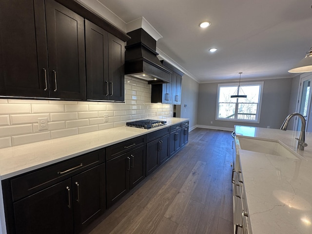 kitchen with custom exhaust hood, light stone countertops, hardwood / wood-style flooring, sink, and backsplash