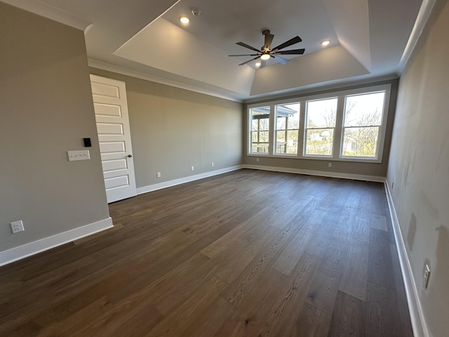 empty room with a raised ceiling, ceiling fan, ornamental molding, and dark hardwood / wood-style floors