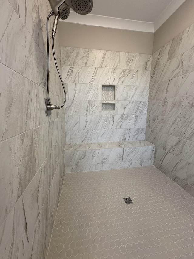 bathroom with ornamental molding and tiled shower