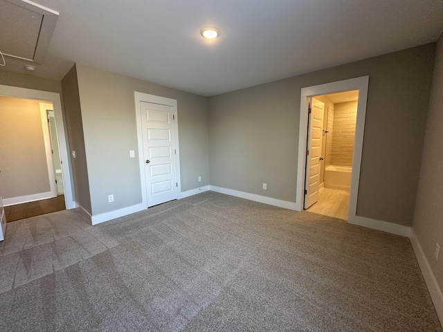 unfurnished bedroom featuring ensuite bath, a closet, and carpet floors