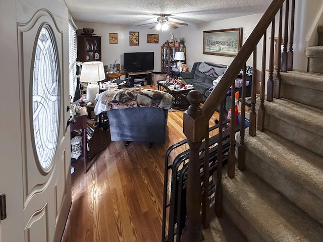 living room featuring ceiling fan, wood-type flooring, and a textured ceiling