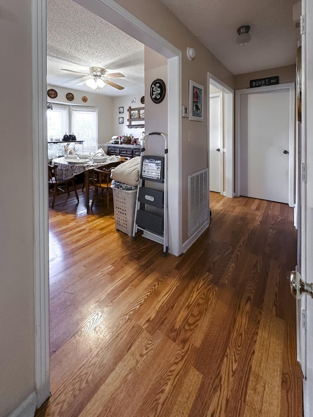 hallway featuring wood-type flooring and a textured ceiling