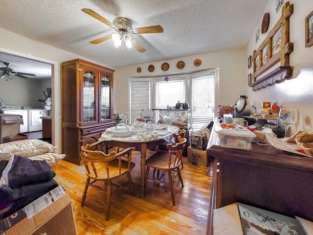 dining space with a textured ceiling, light wood-type flooring, washer and clothes dryer, and ceiling fan