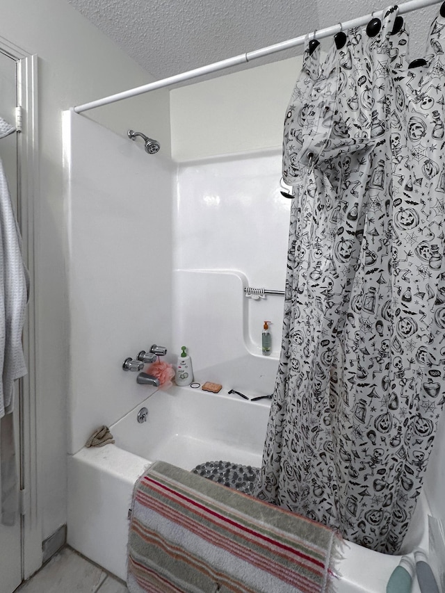 bathroom with a textured ceiling and shower / bath combo with shower curtain