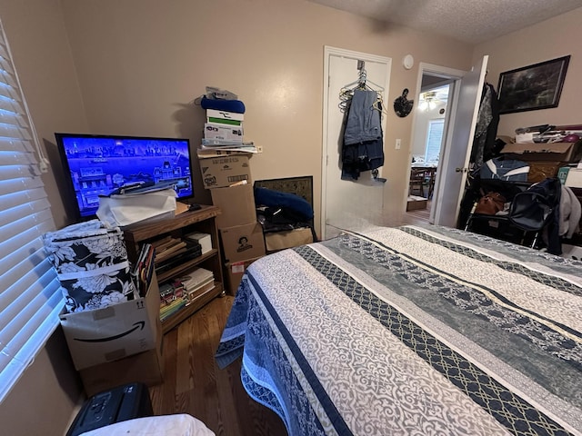 bedroom featuring dark hardwood / wood-style flooring, a textured ceiling, and a closet