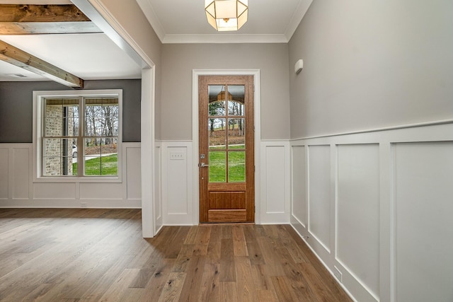 entryway featuring beamed ceiling, hardwood / wood-style flooring, a wealth of natural light, and ornamental molding