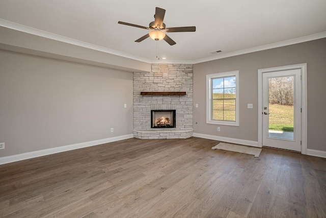 unfurnished living room with a stone fireplace, crown molding, ceiling fan, and hardwood / wood-style flooring