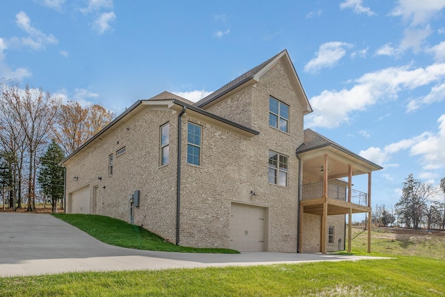 view of side of property featuring a yard, ceiling fan, a balcony, and a garage