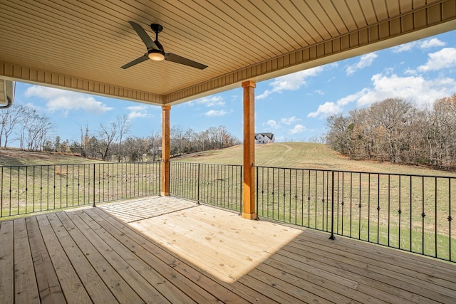 deck with ceiling fan, a yard, and a rural view