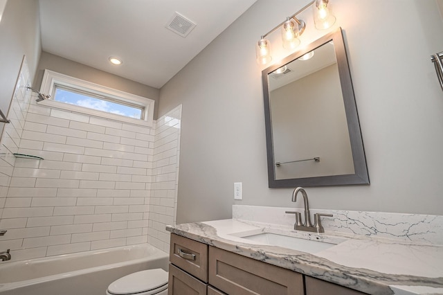 full bathroom featuring vanity, tiled shower / bath combo, and toilet