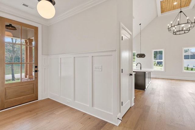 interior space featuring plenty of natural light, an inviting chandelier, hardwood / wood-style floors, and ornamental molding