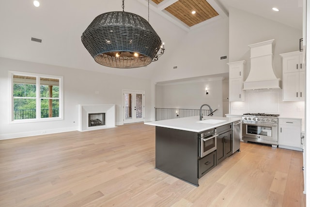 kitchen with custom exhaust hood, high vaulted ceiling, light hardwood / wood-style flooring, appliances with stainless steel finishes, and white cabinetry