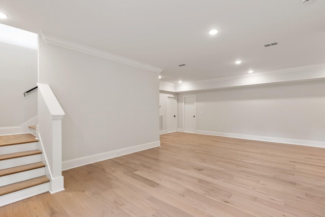 basement with light hardwood / wood-style flooring and ornamental molding