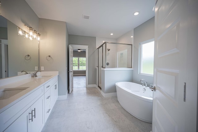 bathroom featuring independent shower and bath, ceiling fan, vanity, and a healthy amount of sunlight