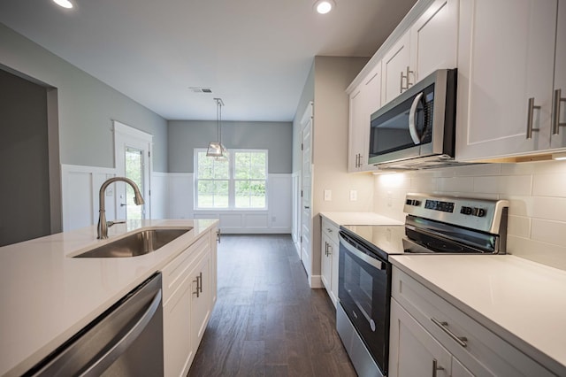 kitchen featuring sink, dark wood-type flooring, pendant lighting, white cabinets, and appliances with stainless steel finishes