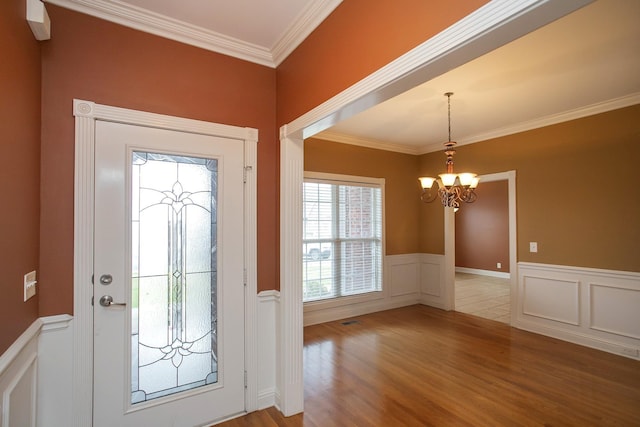 entryway with light wood-type flooring, ornamental molding, and a chandelier