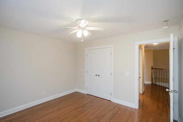 unfurnished bedroom featuring ceiling fan, dark wood-type flooring, and a closet