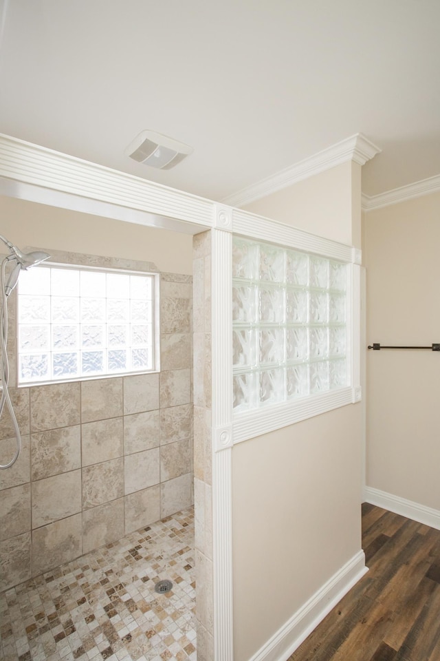 bathroom with tiled shower, wood-type flooring, and ornamental molding