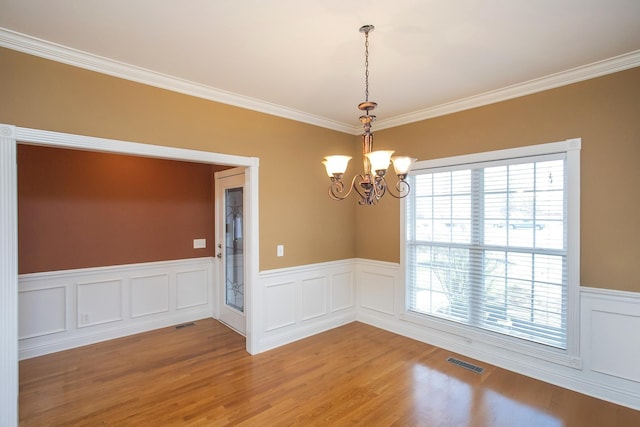 unfurnished room with light hardwood / wood-style floors, an inviting chandelier, plenty of natural light, and crown molding