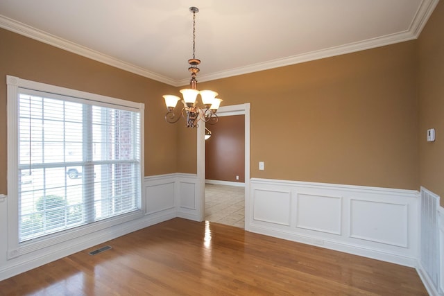 empty room with crown molding, light hardwood / wood-style flooring, and a notable chandelier