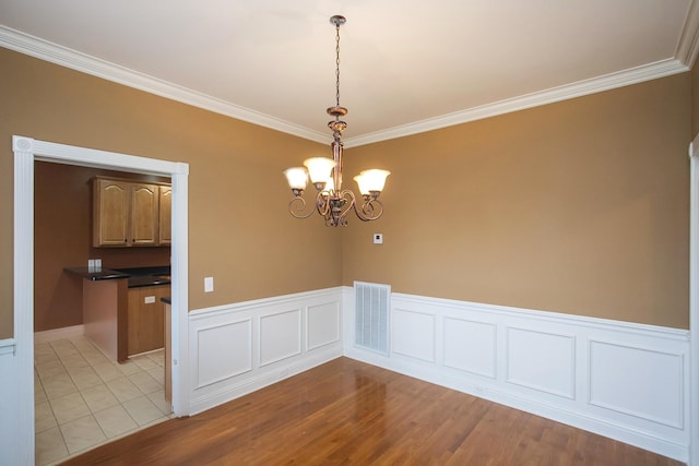 empty room featuring light hardwood / wood-style floors, ornamental molding, and a chandelier