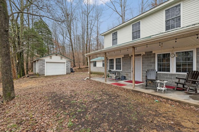 rear view of property featuring an outbuilding, a patio, covered porch, and a garage