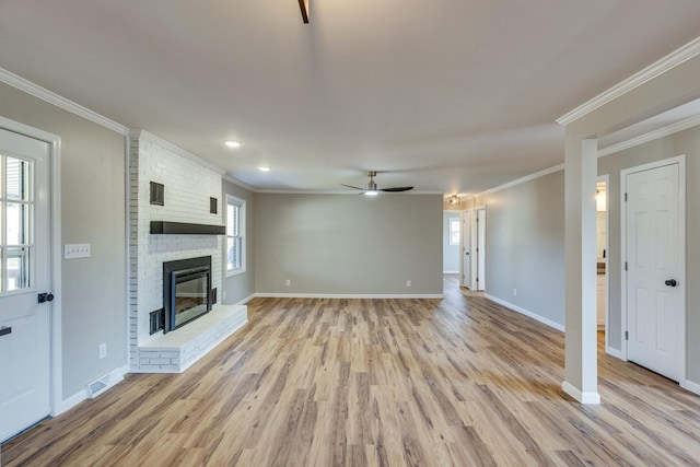 unfurnished living room with ceiling fan, ornamental molding, a fireplace, and plenty of natural light