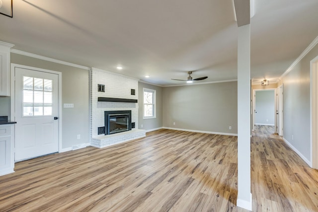 unfurnished living room featuring ceiling fan, a fireplace, crown molding, and light wood-type flooring