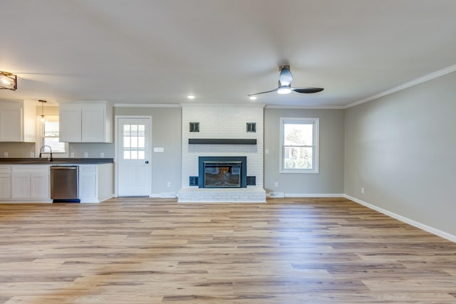 unfurnished living room with ceiling fan, a healthy amount of sunlight, crown molding, and light wood-type flooring