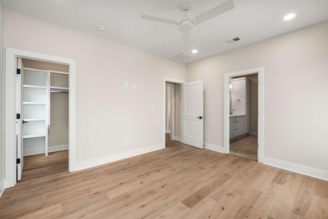 unfurnished bedroom featuring connected bathroom, a closet, light hardwood / wood-style flooring, and ceiling fan