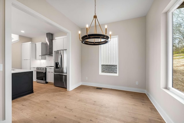 kitchen featuring a wealth of natural light, light hardwood / wood-style flooring, wall chimney exhaust hood, and appliances with stainless steel finishes