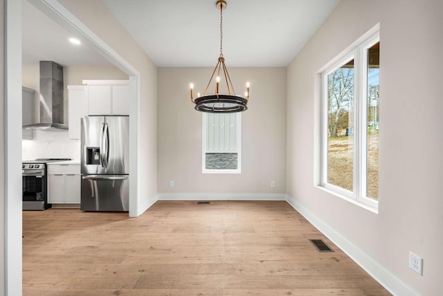 unfurnished dining area with light hardwood / wood-style floors and a notable chandelier