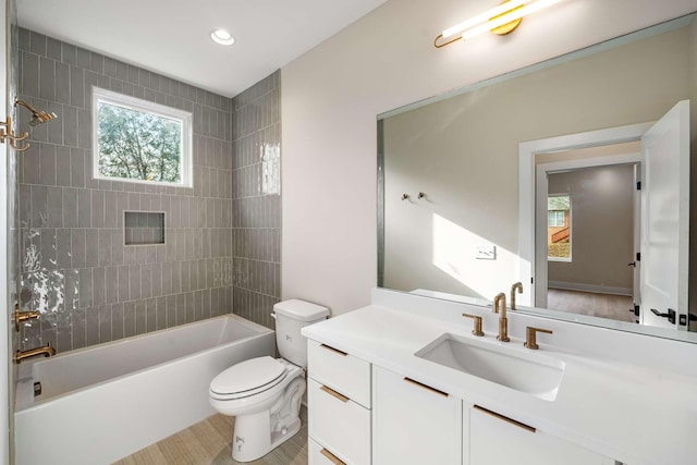 full bathroom featuring vanity, tiled shower / bath combo, and toilet