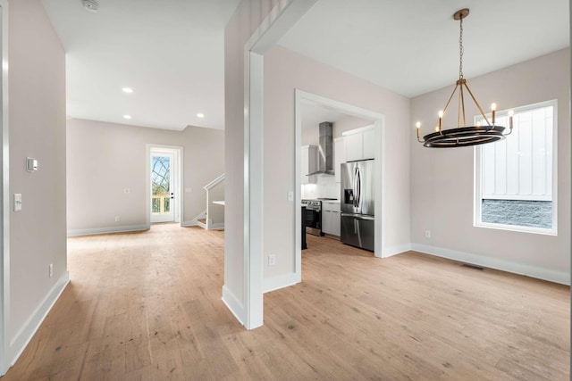 unfurnished dining area featuring light hardwood / wood-style flooring and a notable chandelier