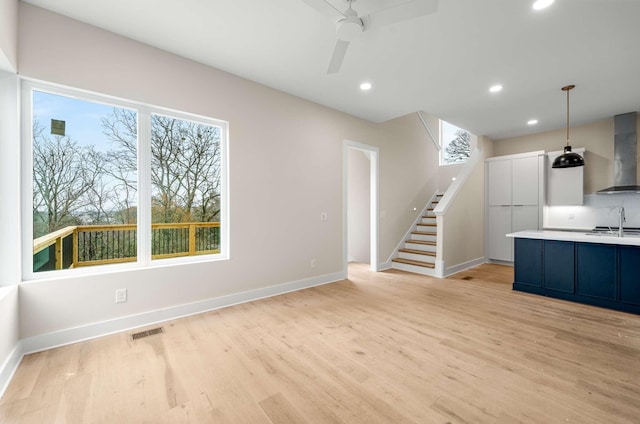 unfurnished living room with light hardwood / wood-style flooring and ceiling fan