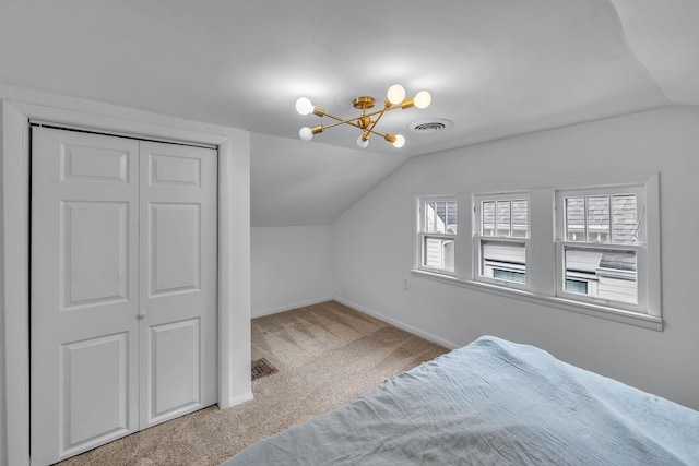 carpeted bedroom featuring an inviting chandelier, a closet, and lofted ceiling