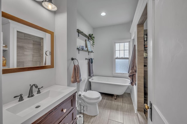 bathroom featuring a washtub, vanity, and toilet