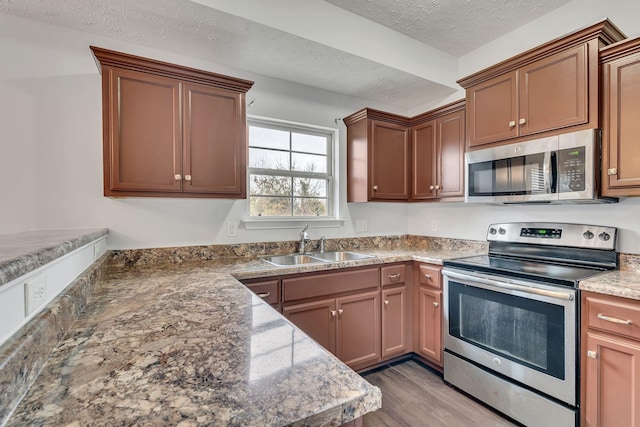 kitchen featuring hardwood / wood-style floors, sink, dark stone countertops, a textured ceiling, and stainless steel appliances